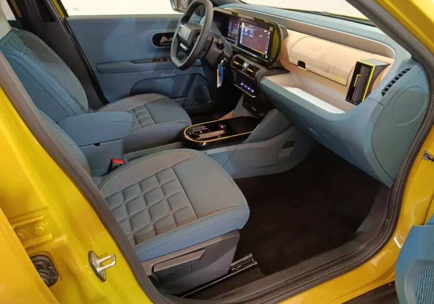 Vue intérieure côté conducteur de la Fiat Grande Panda jaune 2025, avec sièges gris et tableau de bord moderne tactile.