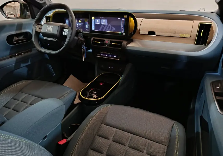 Vue intérieure avant droite de la Fiat Grande Panda jaune, tableau de bord moderne avec écran tactile et volant cuir noir.
