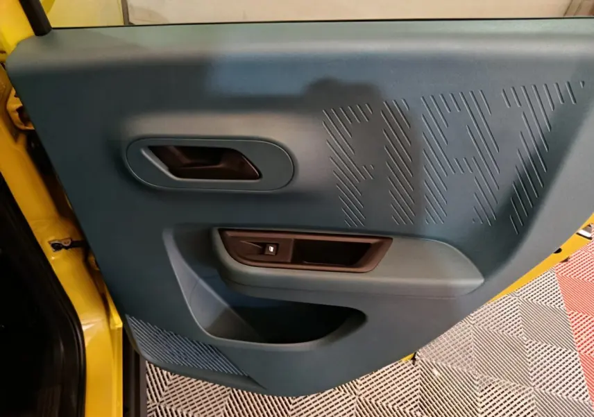 Vue rapprochée de la porte intérieure côté conducteur de la Fiat Grande Panda jaune avec logo FIAT en relief.
