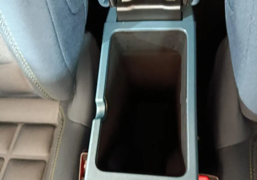 Vue plongeante sur la console centrale ouverte entre les sièges avant bleu foncé de la Fiat Grande Panda jaune.