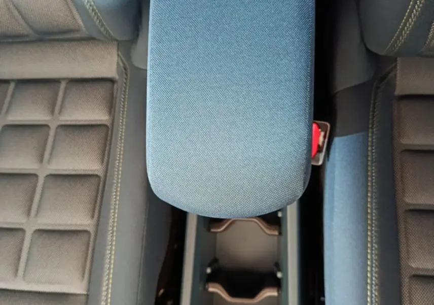 Vue plongeante sur l'accoudoir central bleu et les sièges avant avec surpiqûres jaunes de la Fiat Grande Panda 2025.