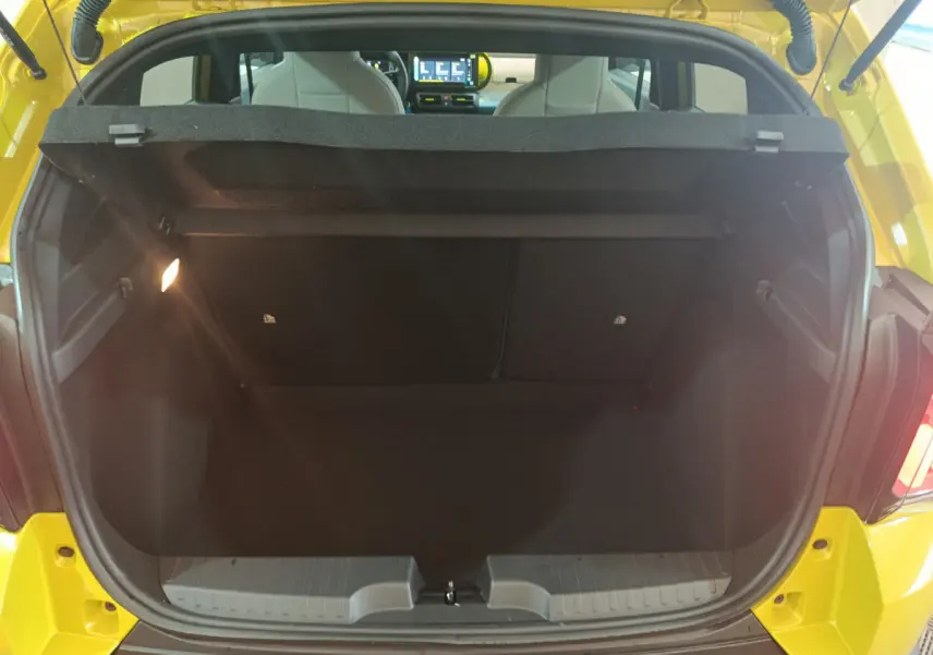 Coffre ouvert d'une FIAT Grande Panda jaune vue arrière, intérieur noir avec tablette de séparation et sièges blancs visibles.