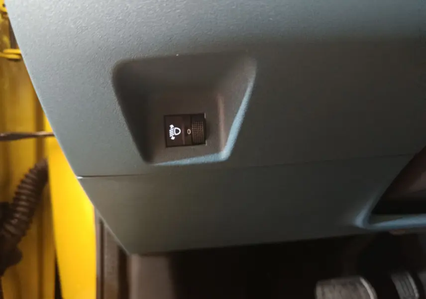Gros plan sur le réglage d'inclinaison des phares côté conducteur dans une Fiat Grande Panda jaune 2025.
