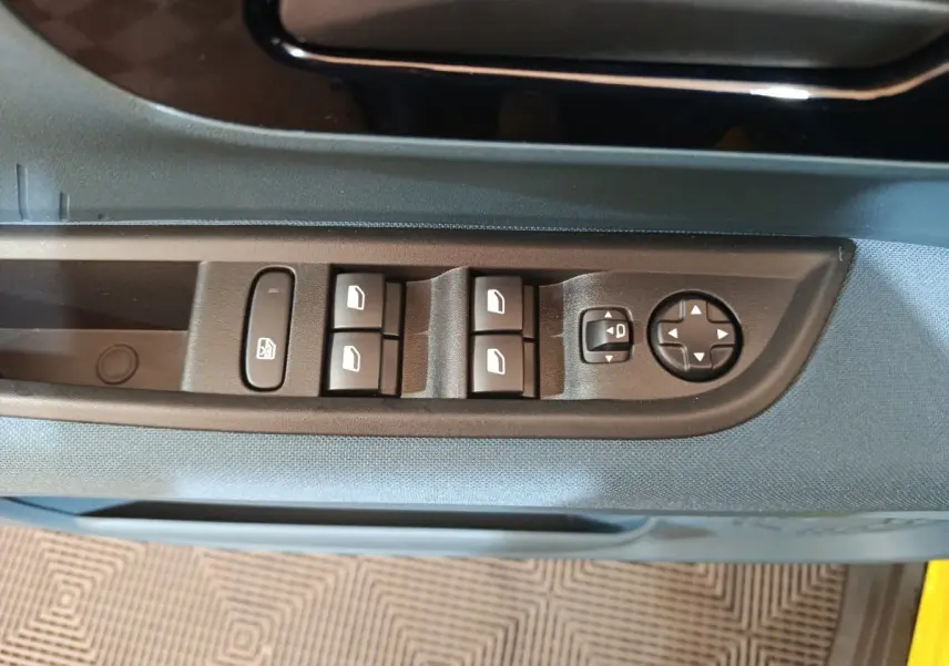 Gros plan sur les commandes des vitres et rétroviseurs côté conducteur de la FIAT Grande Panda jaune 2025.