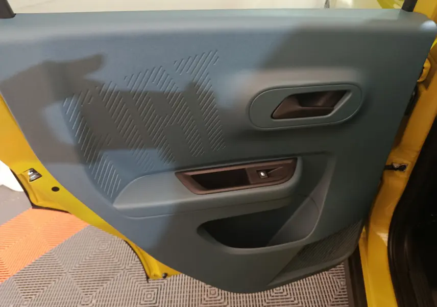 Vue intérieure de la porte avant gauche bleue avec poignée et bouton de verrouillage, cadre jaune visible FIAT Grande Panda 2025.