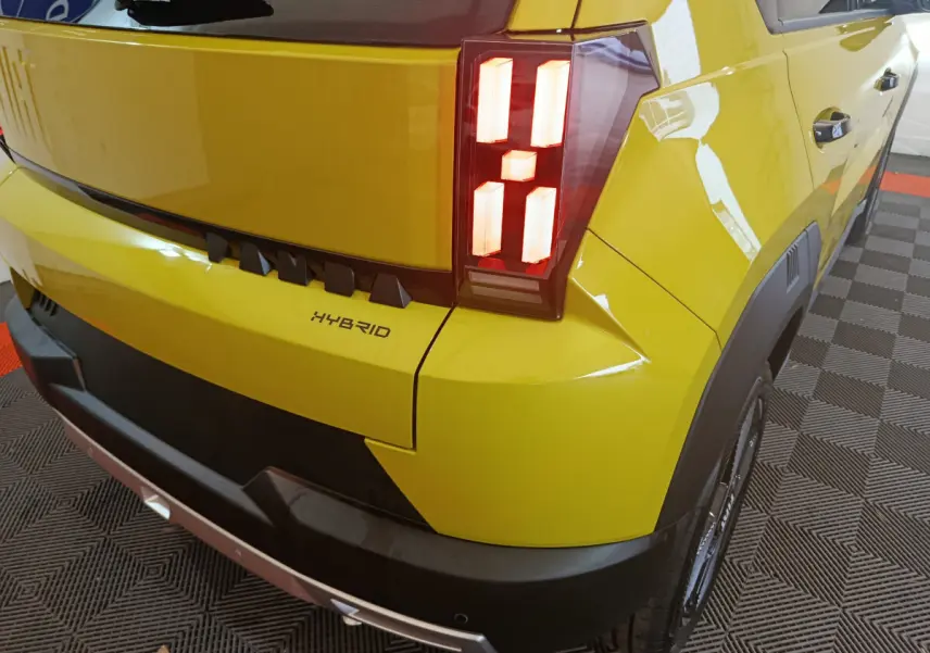 Vue 3/4 arrière droite d'une FIAT Grande Panda jaune 2025 avec feux arrière LED et badge Hybrid visible.