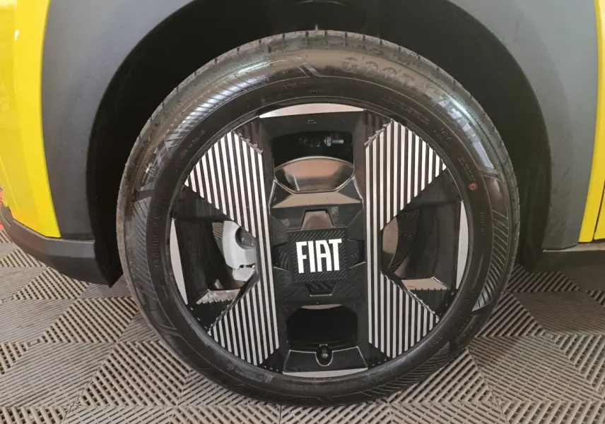 Gros plan sur la roue avant droite noire et argentée avec logo FIAT, partie basse jaune de la Fiat Grande Panda visible.