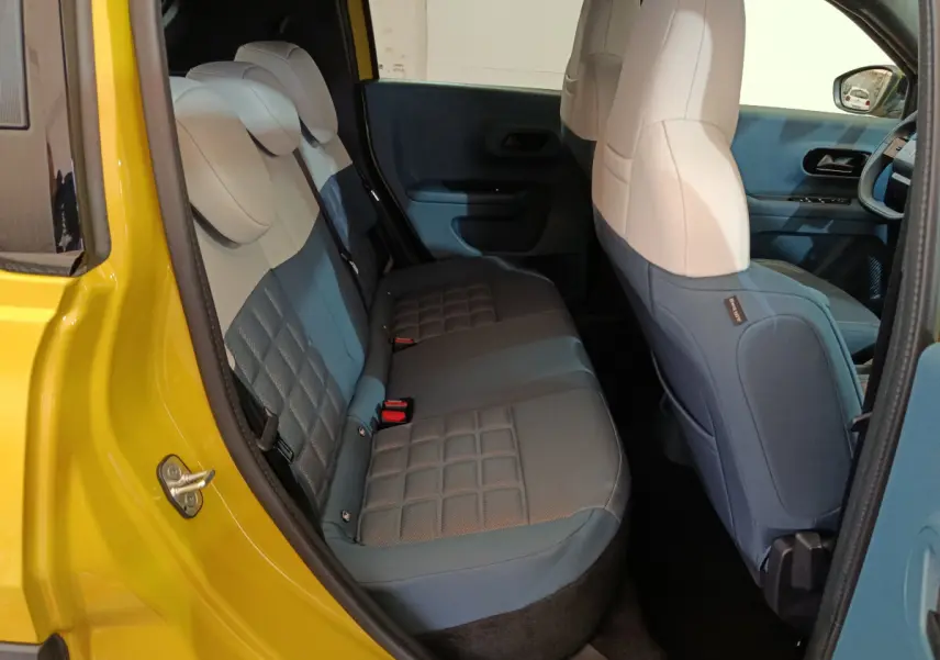 Vue intérieure arrière côté gauche de la Fiat Grande Panda jaune, montrant la banquette bi-ton bleu et beige.