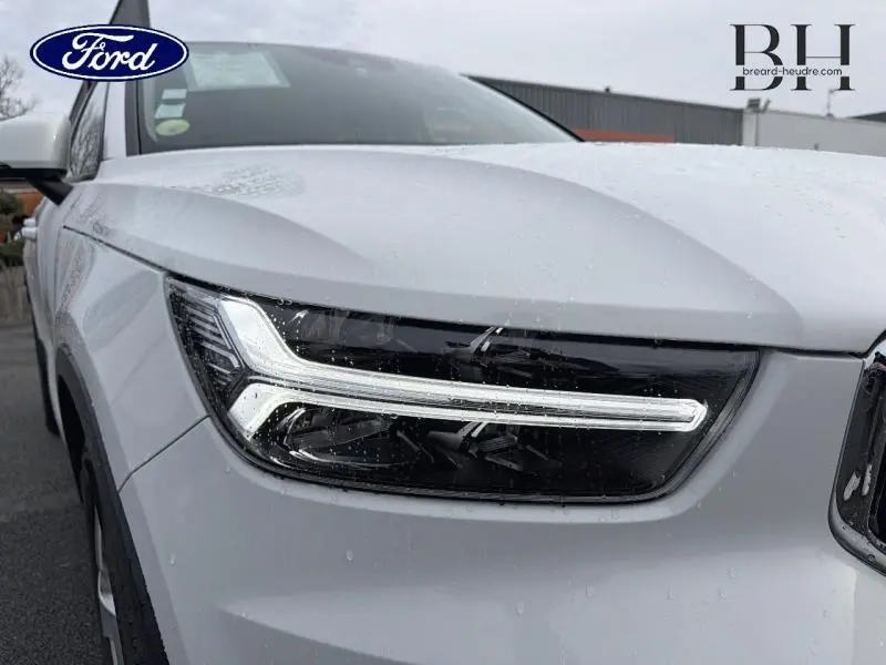 Gros plan sur le phare avant gauche blanc glace du Volvo XC40 D4 AdBlue AWD 2018 sous la pluie.