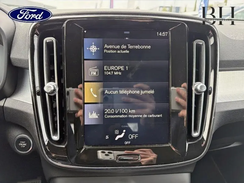 Écran tactile central du tableau de bord d’un Volvo XC40 blanc, affichant navigation et consommation.