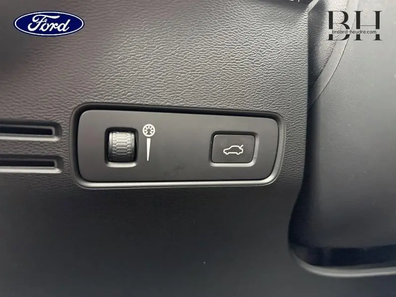 Gros plan sur les commandes intérieures noires du coffre et du réglage de luminosité d'un Volvo XC40 blanc Glace.