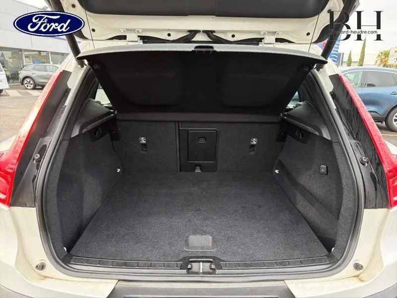 Coffre ouvert vu de l'arrière d'un Volvo XC40 blanc glace, avec intérieur de coffre gris et banquette rabattable.