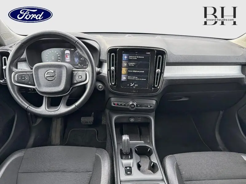 Vue intérieure frontale du tableau de bord noir et gris du Volvo XC40 D4 Business avec écran tactile central et volant cuir.