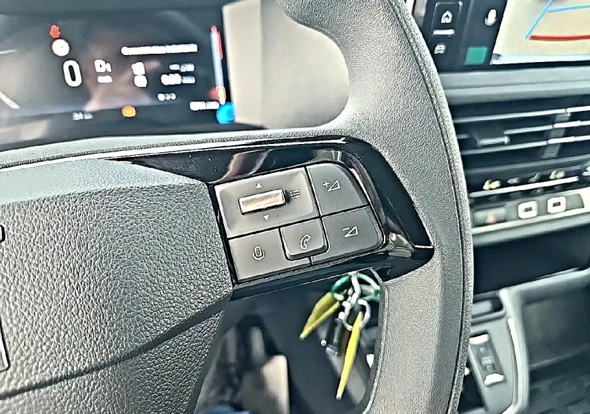 Gros plan sur le volant noir du Fiat Scudo Combi 2026 avec commandes audio et affichage numérique en arrière-plan.