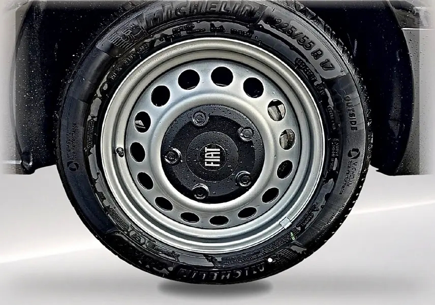 Gros plan sur la roue avant droite noire du Fiat Scudo Combi avec jante acier grise et logo central Fiat.