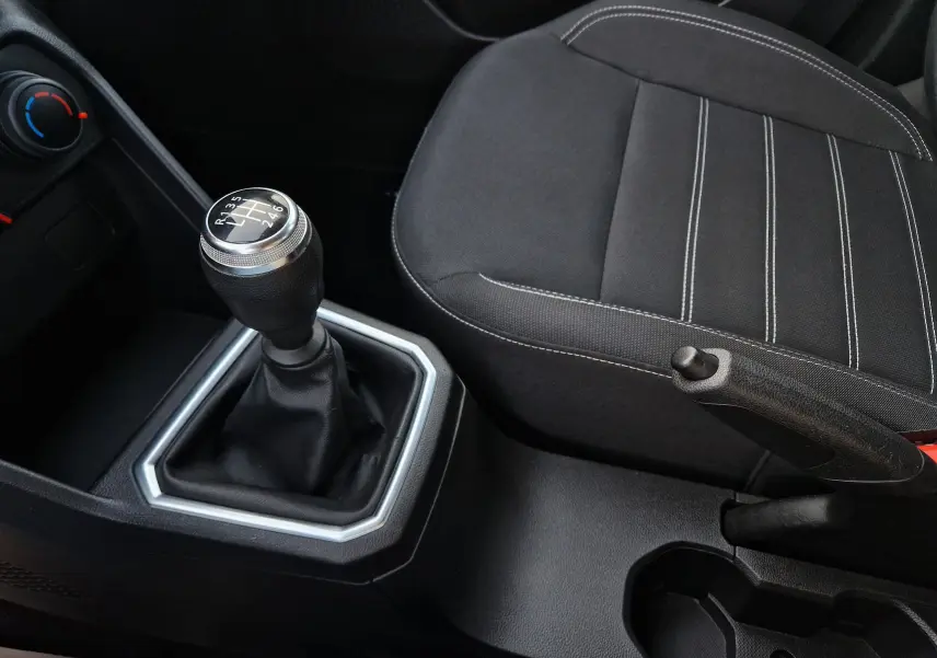 Vue rapprochée de la console centrale de la Dacia Sandero blanche 2022, avec levier de vitesse manuel et siège tissu noir.