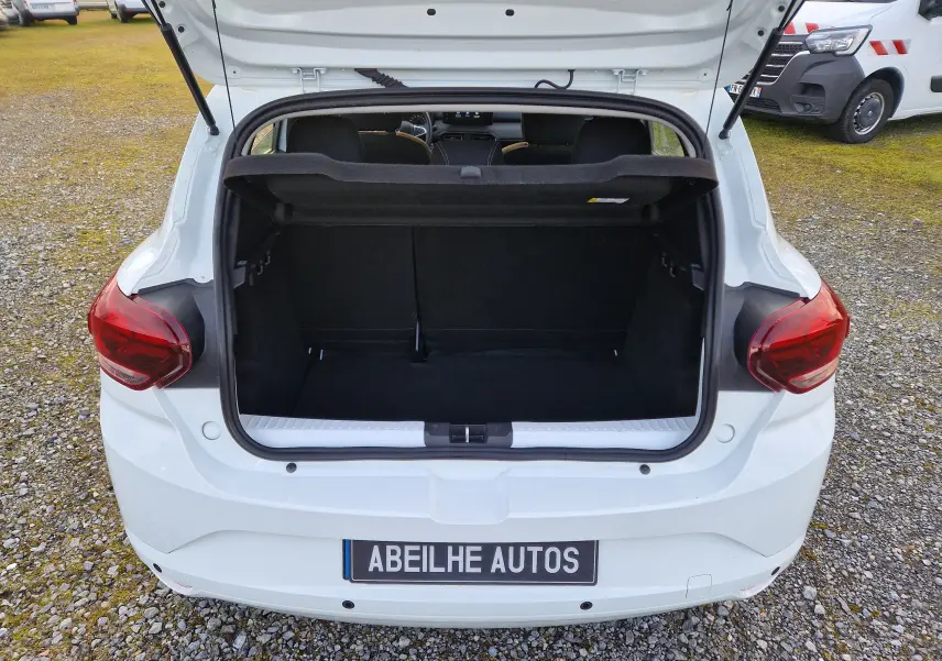 Vue arrière ouverte du coffre d'une Dacia Sandero blanche 2022, avec intérieur noir et hayon relevé.