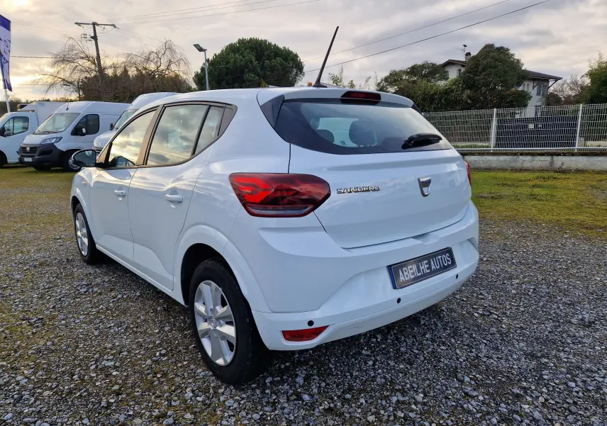 Vue 3/4 arrière droite d'une Dacia Sandero blanche 2022 avec feux arrière LED et antenne sur le toit.