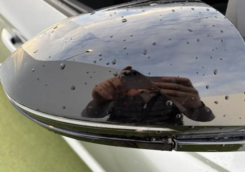 Gros plan sur le rétroviseur extérieur noir brillant du Hyundai Tucson 2025 en Shimmering Silver, avec gouttes d'eau visibles.