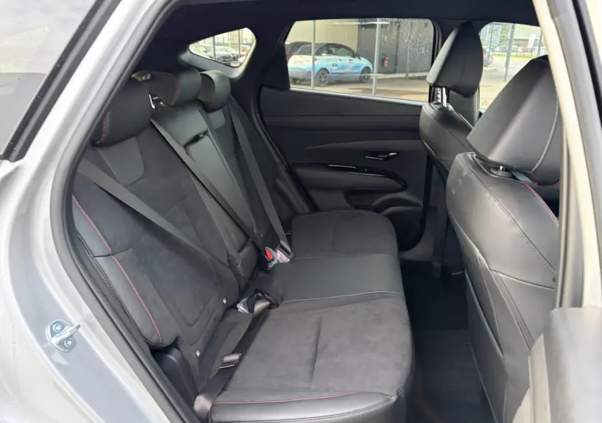 Vue intérieure côté gauche des sièges arrière cuir/alcantara noirs avec surpiqûres rouges du Hyundai Tucson 2025 Shimmering Silver.