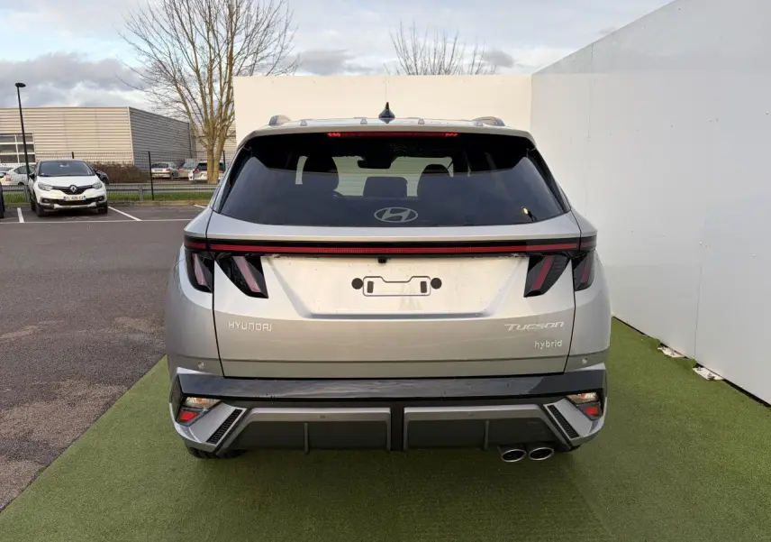 Vue arrière d'un Hyundai Tucson 2025 hybride en argent métallisé avec feux arrière LED et double sortie d'échappement côté droit.