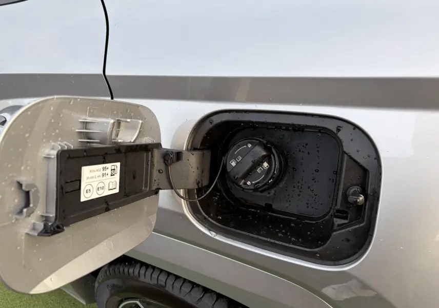Trappe de carburant ouverte côté gauche d’un Hyundai Tucson 2025 gris argent métallisé avec bouchon noir et gouttes d’eau.