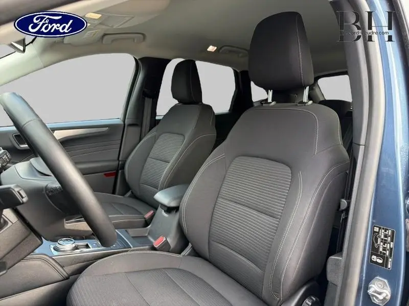 Vue intérieure côté conducteur du Ford Kuga 2022 bleu azur, sièges avant sport noirs avec accoudoir central.