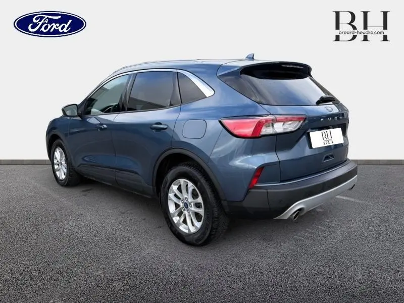 Ford Kuga bleu azur métallisé vu en 3/4 arrière droit avec vitres arrière surteintées et jantes alu.