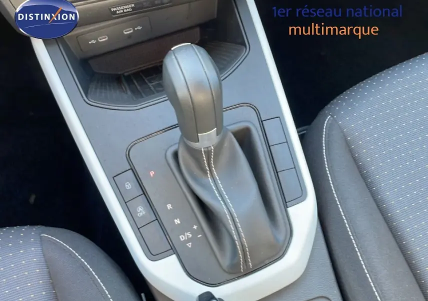 Le levier de vitesse automatique en cuir noir de la SEAT Arona 2025, avec coutures blanches et sièges tissu gris.