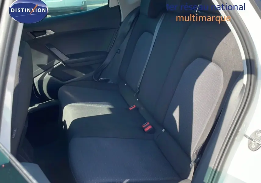 Vue intérieure des sièges arrière noirs d'un SEAT Arona blanc métal avec toit noir, montrant les ceintures de sécurité et la porte ouverte côté droit.