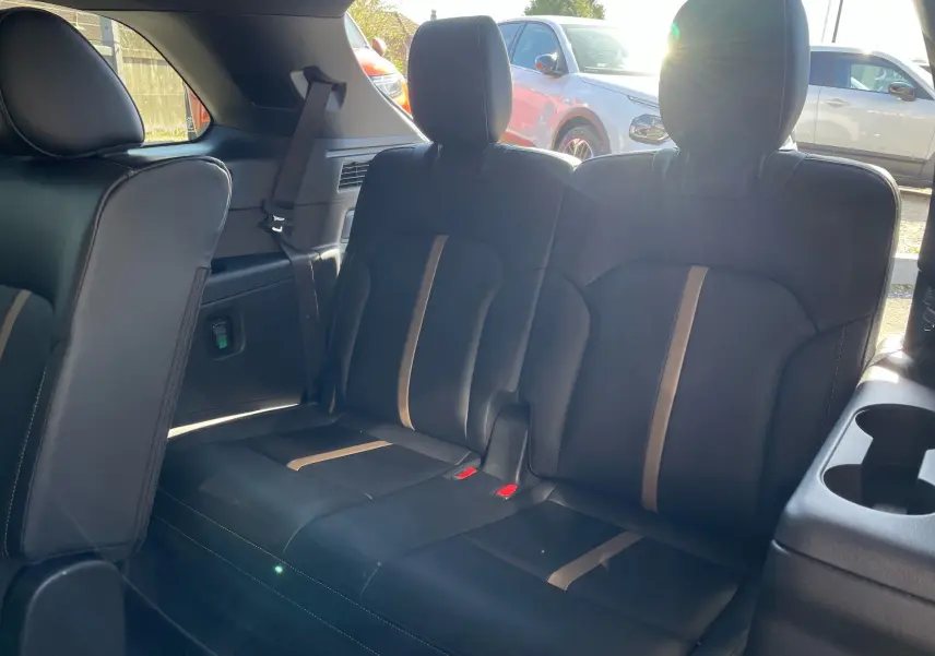 Vue intérieure sur la banquette arrière en cuir noir avec surpiqûres et bandes beiges du Mazda CX-80 2024 Artisan Red.