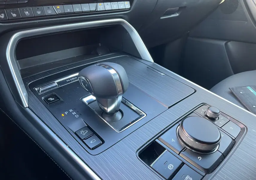 Gros plan sur la console centrale noire du Mazda CX-80 2024 avec levier de vitesse automatique et commandes intégrées.