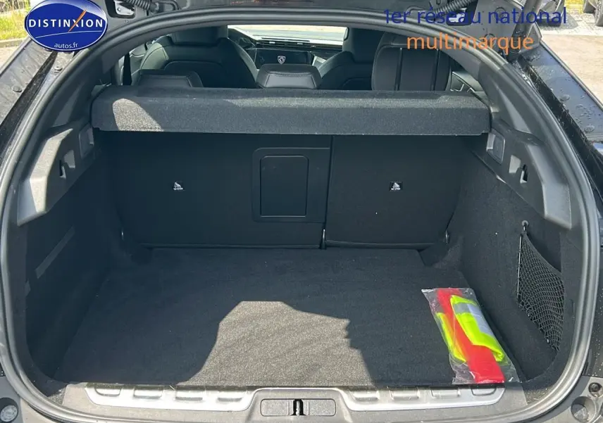 Coffre ouvert d'une Peugeot 408 Hybrid 145 GT noir, vue arrière montrant l'espace de chargement et la banquette arrière.