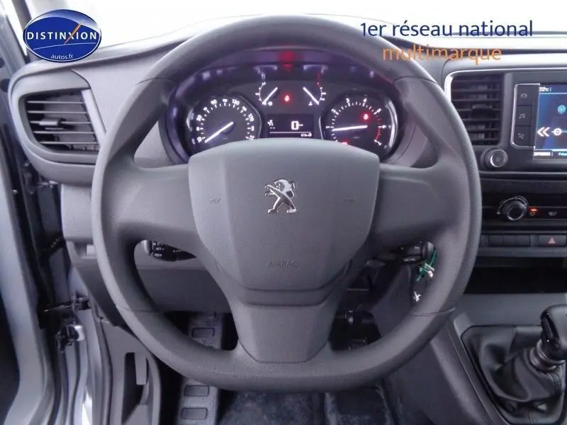 Vue rapprochée du volant Peugeot Expert Fourgon gris acier, tableau de bord et commandes visibles côté conducteur.