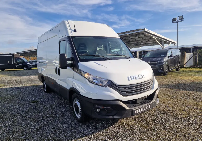Fourgon Iveco Daily blanc vu en 3/4 avant droit sur un parking extérieur avec ciel bleu.