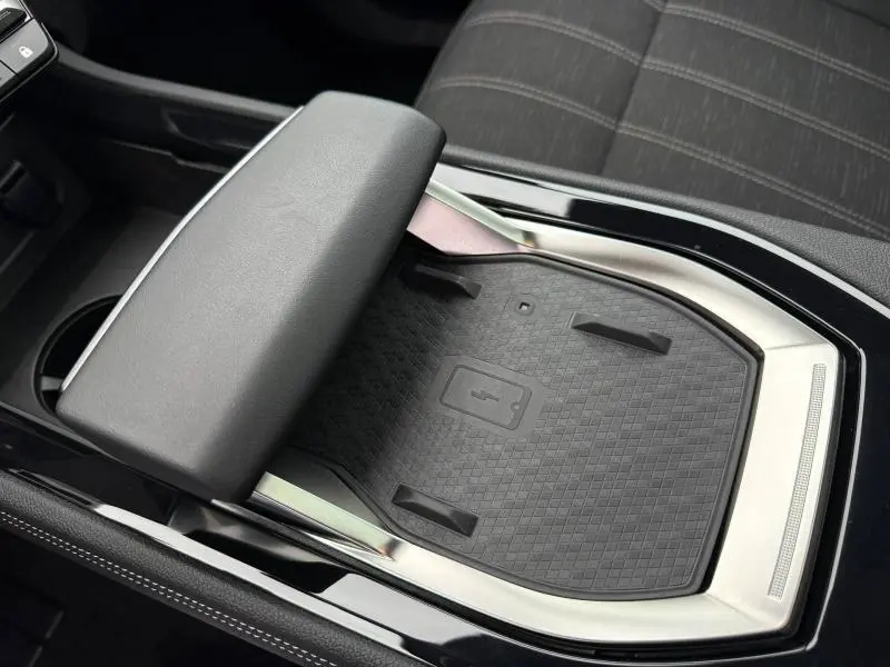 Gros plan sur le chargeur sans fil et accoudoir central du Renault Austral 2025, intérieur noir avec surpiqûres grises.