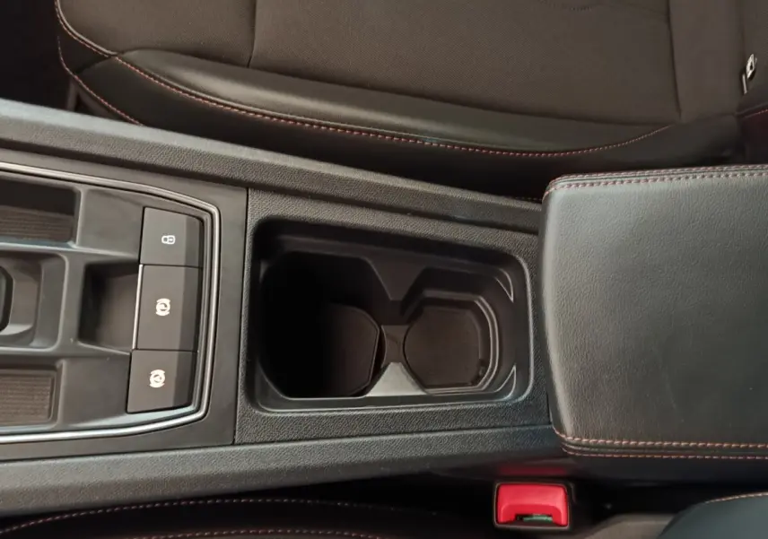 Vue rapprochée de la console centrale noire du CUPRA Formentor 2024 avec porte-gobelets et accoudoir en cuir surpiqué rouge.