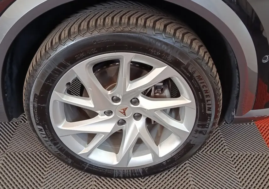 Gros plan sur la roue avant droite d'une CUPRA Formentor noire avec jante argentée et logo CUPRA central.