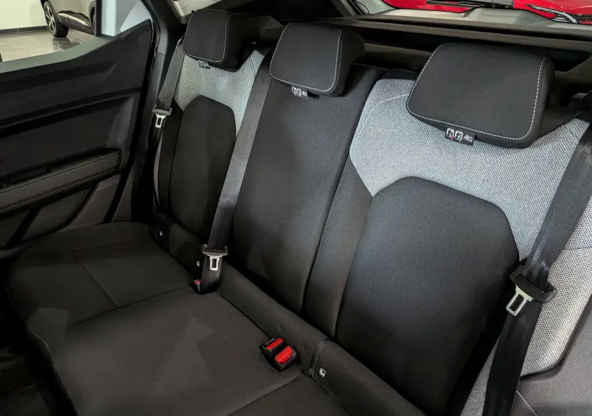 Vue intérieure des sièges arrière noirs et gris du Dacia Duster Hybrid-G 150 CH 4x4 Journey, avec ceintures de sécurité visibles.