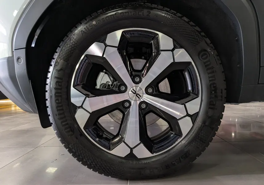 Gros plan sur la roue avant droite du Dacia Duster blanc Glacier, jante alliage bicolore et pneu Continental.