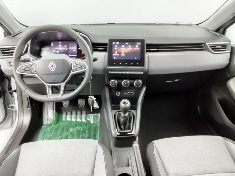 Intérieur avant de la Renault Clio gris schiste 2025, vue du tableau de bord avec volant multifonction et boîte manuelle.