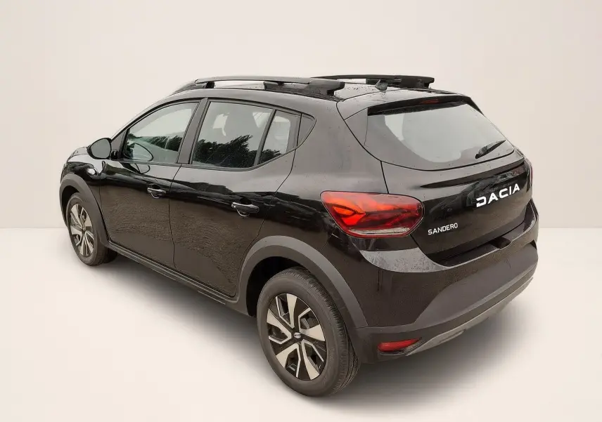 Vue 3/4 arrière droite d'une Dacia Sandero Stepway noire nacrée avec barres de toit et jantes 16 pouces.