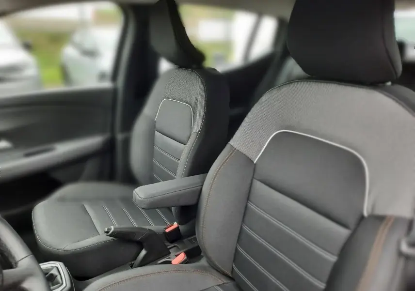 Gros plan sur les sièges avant gris avec accoudoir central dans l'habitacle d'une Dacia Sandero Stepway 2025.