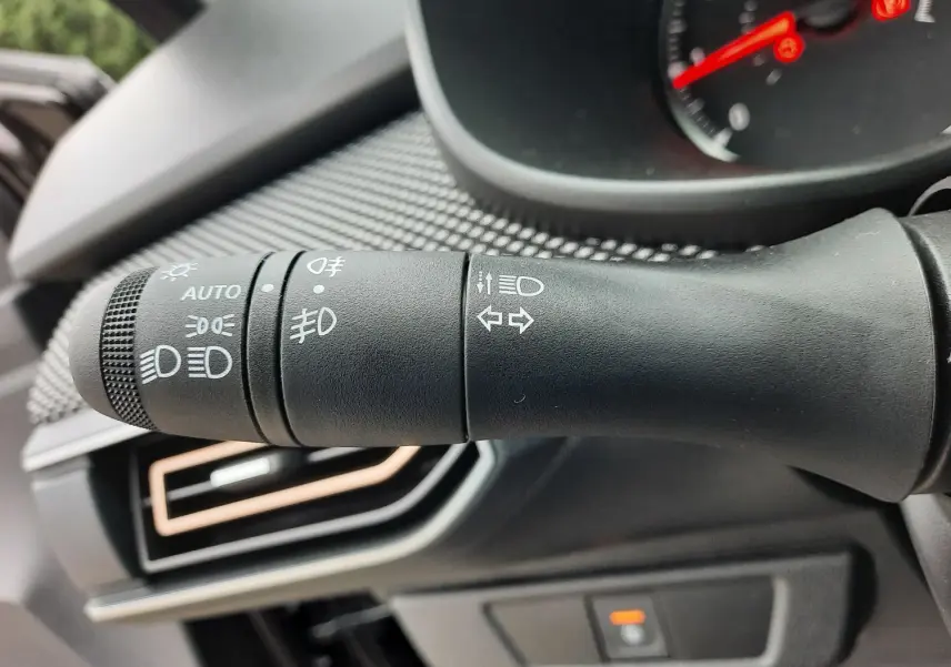 Gros plan sur la commande des phares et clignotants dans l'habitacle d'une Dacia Sandero Stepway noir nacré 2025.