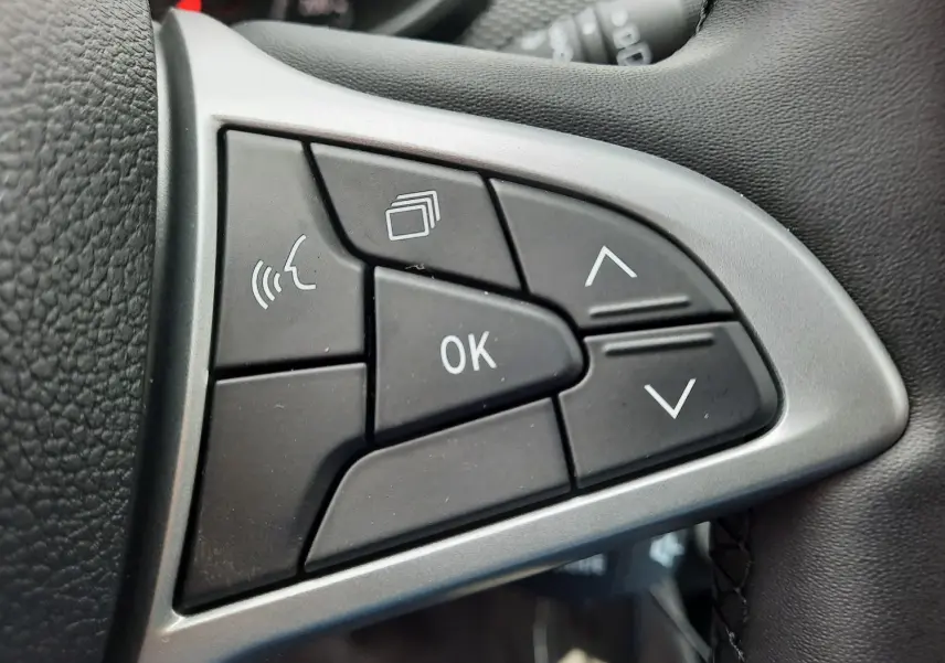 Gros plan sur les commandes multifonctions noires du volant cuir de la Dacia Sandero Stepway 2025.