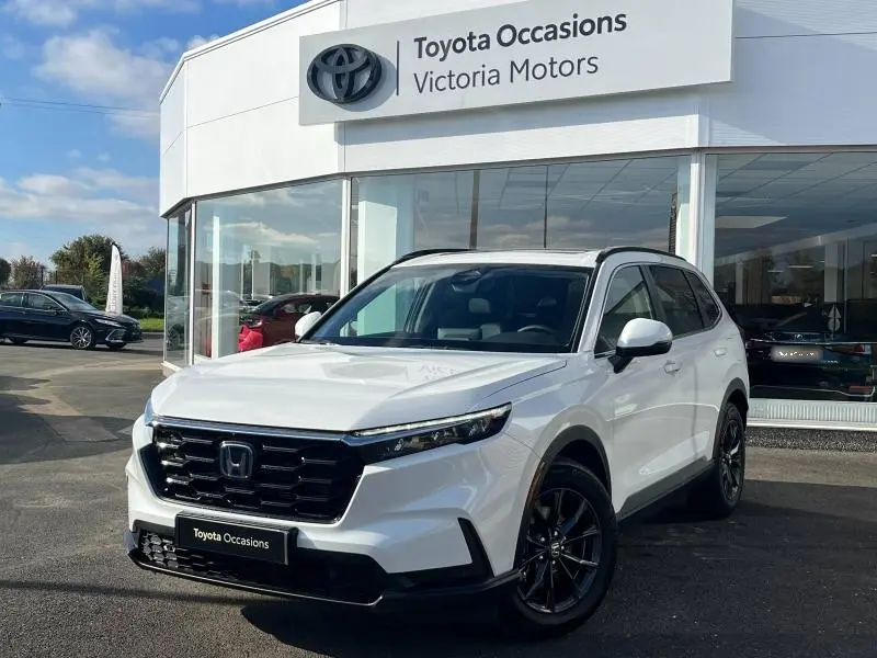 Honda CR-V 2024 blanc diamant métallisé en 3/4 avant droit avec calandre noire et jantes foncées, devant concession Toyota.