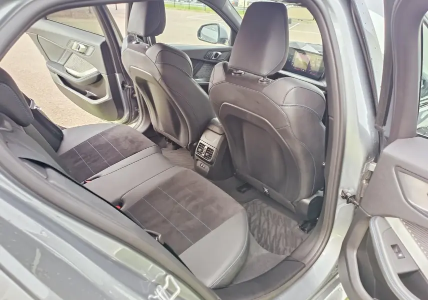 Vue intérieure arrière côté gauche de la BMW Série 1 120 M Sport gris Skyscraper avec sellerie Alcantara noire et surpiqûres bleues.