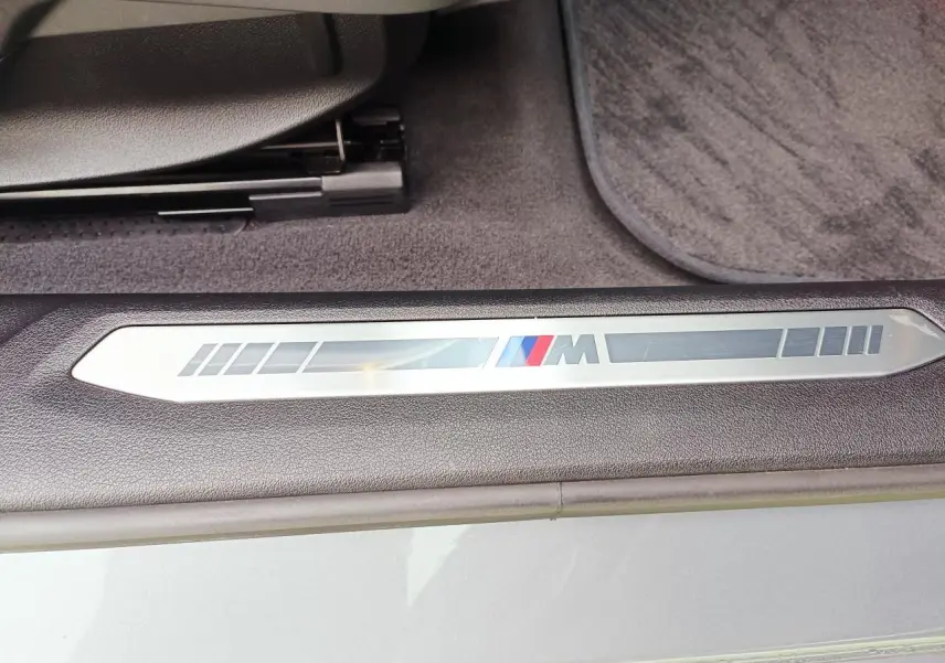 Détail de la plaque M sur le seuil de porte côté conducteur d'une BMW Série 1 gris Skyscraper avec intérieur noir.