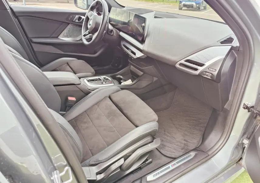 Vue intérieure côté conducteur de la BMW Série 1 M Sport 2025, sièges Alcantara noirs et tableau de bord moderne.