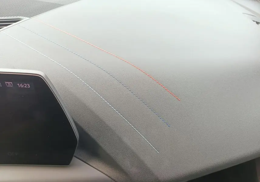 Détail du tableau de bord gris avec surpiqûres tricolores bleu clair, bleu foncé et rouge sur BMW Série 1 F70.